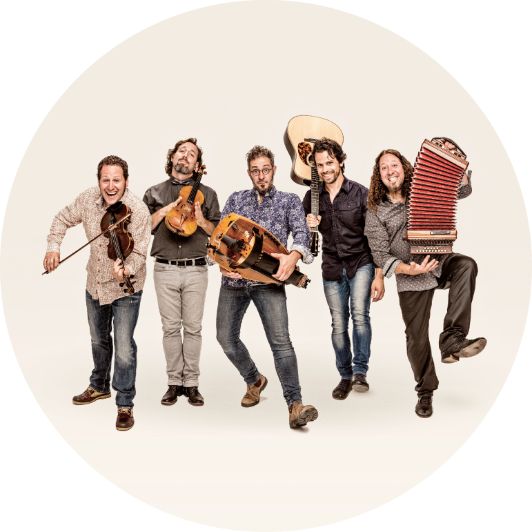 The members of Le Vent du Nord wear casual dress and stand in a line holding their instruments..