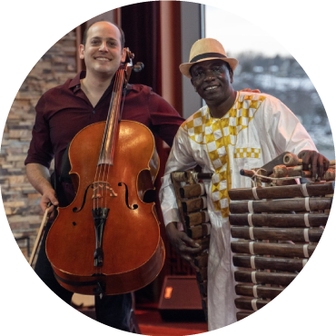 Mike Block and Balla Kouyaté stand together against a window holding their instruments